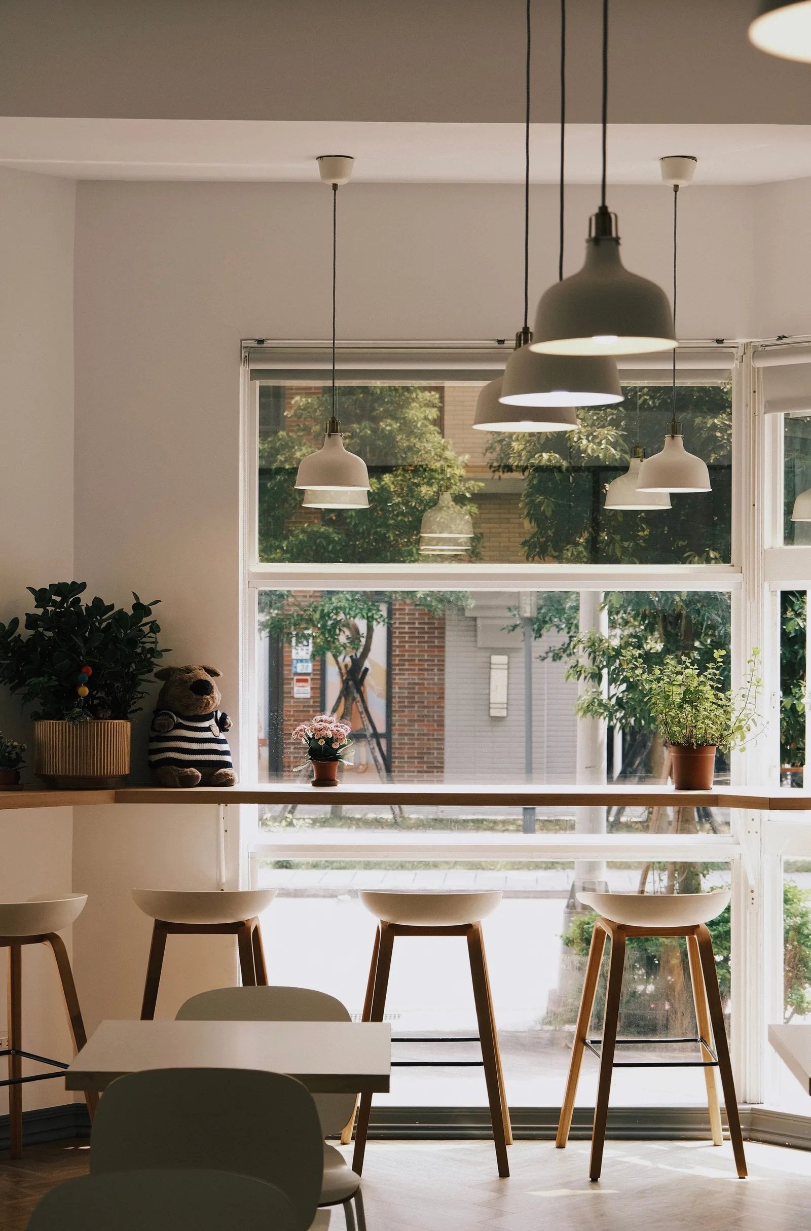 Bright cafe interior with pendant lamps, stools and a large window